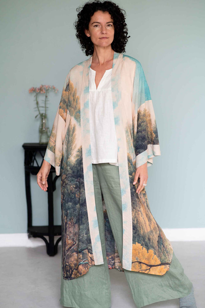 Woman in Awakening Opera duster, white top, green pants.