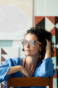 Bella Champagne Fara wearing sunglasses, portrait with clouds background.