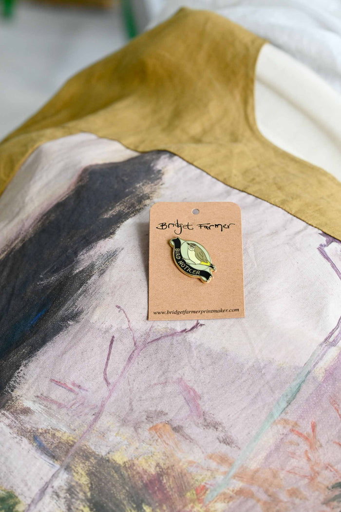 Bird Noticer pin on abstract patterned fabric