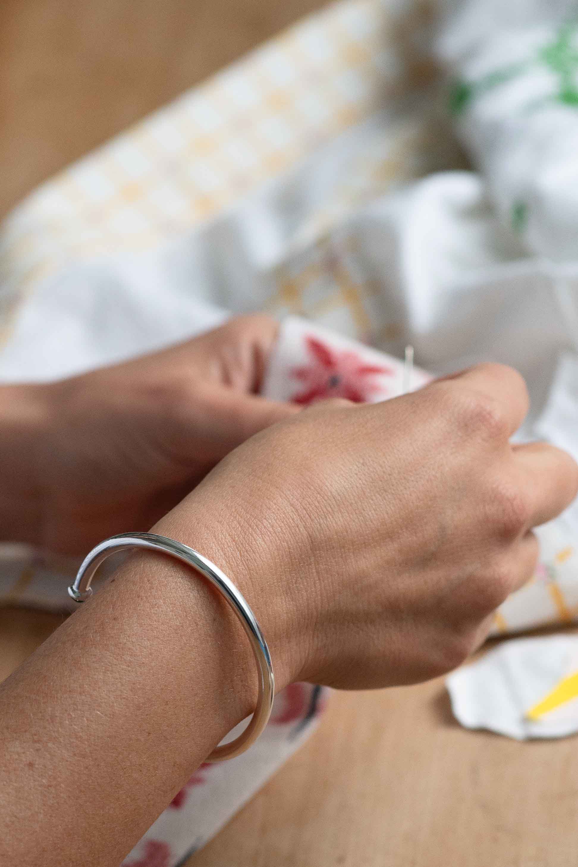 Silver bracelet on wrist, holding fabric