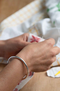 Silver bracelet on wrist, holding fabric