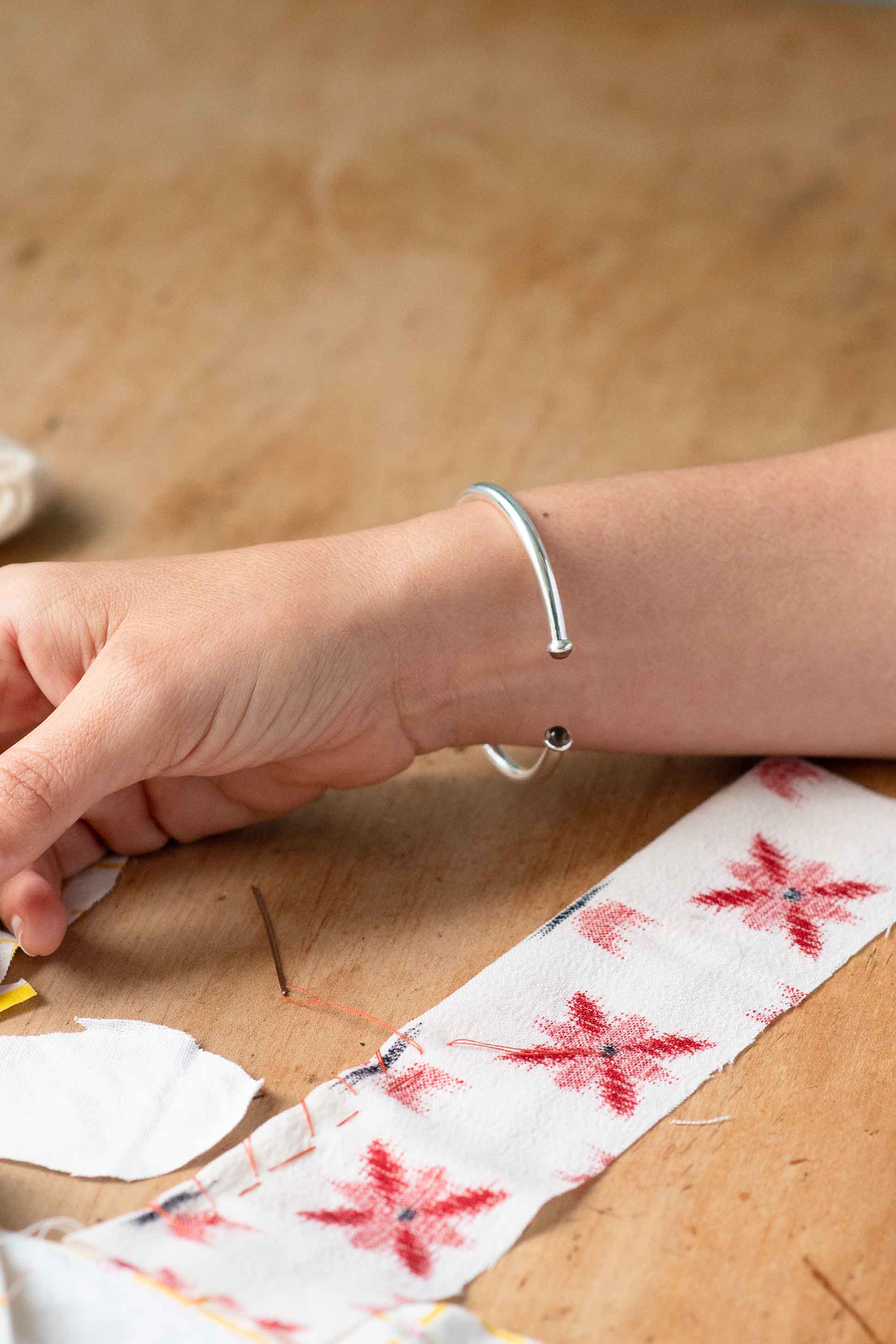 Silver bracelet on wrist with red floral fabric