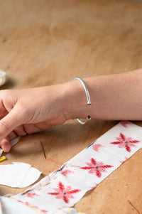 Silver bracelet on wrist with red floral fabric