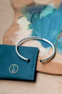 Silver bracelet with black accents on teal pouch
