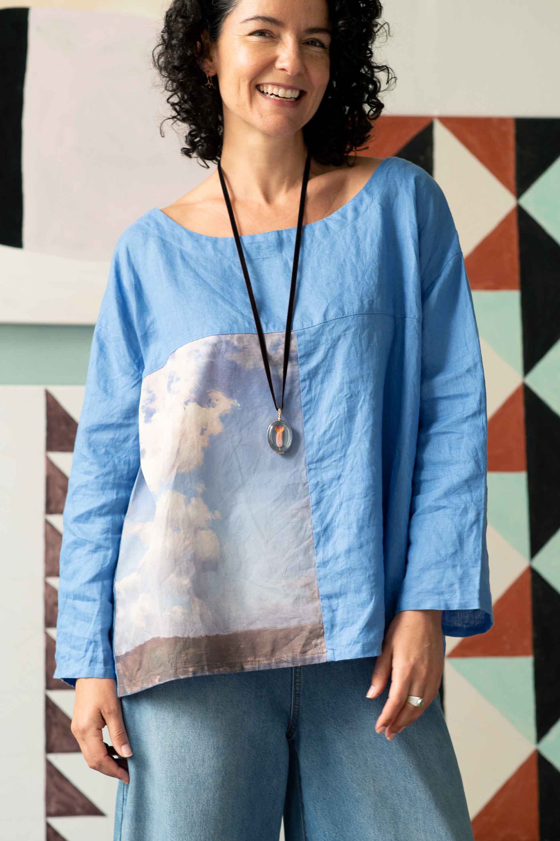 Woman in blue denim and cloud top with crystal locket.