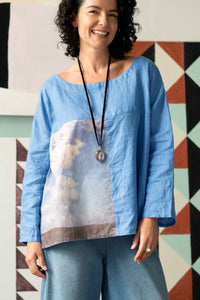 Woman in blue denim and cloud top with crystal locket.