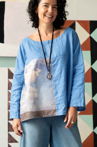 Woman in blue denim and cloud top with crystal locket.
