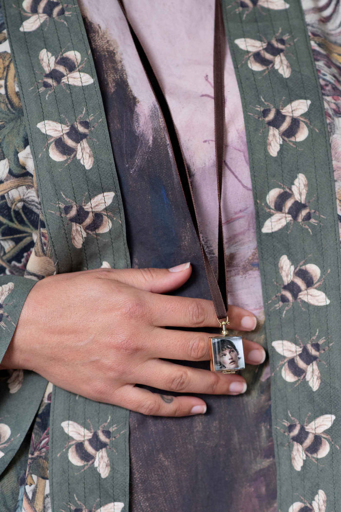 Crystal locket on a woman with bee-patterned jacket.