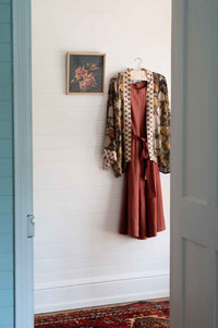 Dress and jacket hanging on a white wall.