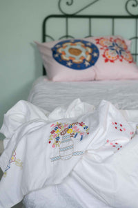 Embroidered bedding with decorative pillows on a bed frame, DSC4686