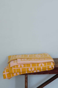Yellow daisy throw blanket folded on wooden surface