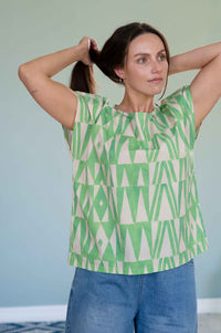 EleanorGeo top, green geometric pattern, woman adjusting ponytail