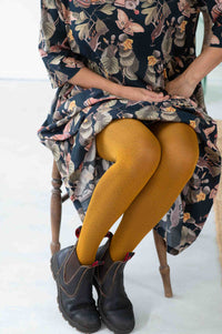 Woman in floral dress, Geo Ochre tights, and boots.