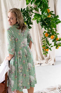 Gianna Newlyn in floral dress, citrus tree in background.