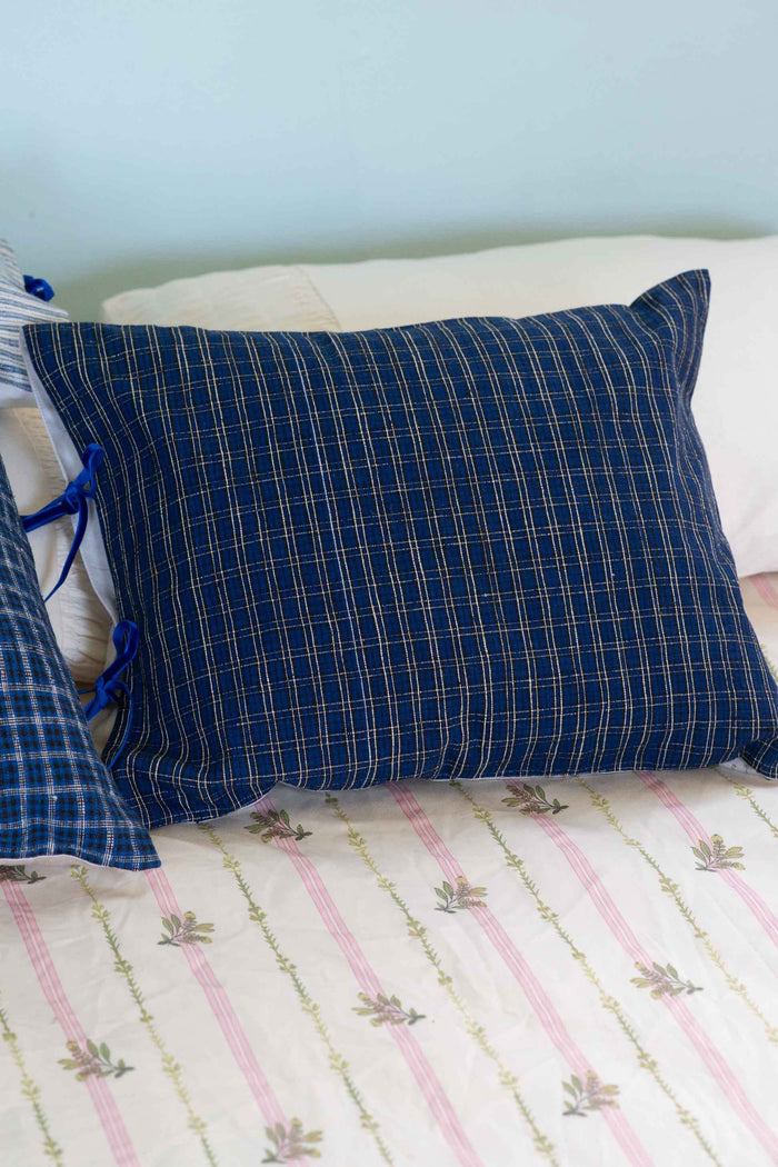 Handwoven blue plaid cushion on bed