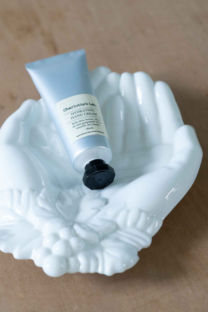 Hydrating hand cream tube in decorative hand dish