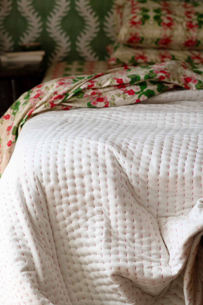 Kantha quilt on bed with floral sheets
