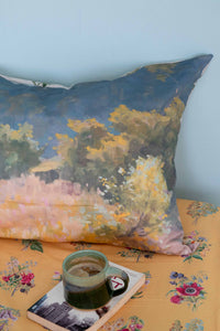 Landscape painting pillow with coffee cup on floral bed