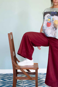 Ollie Red pants with foot on wooden chair.