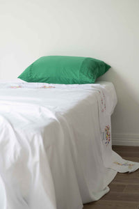 Homespun white sheet with green pillow on bed