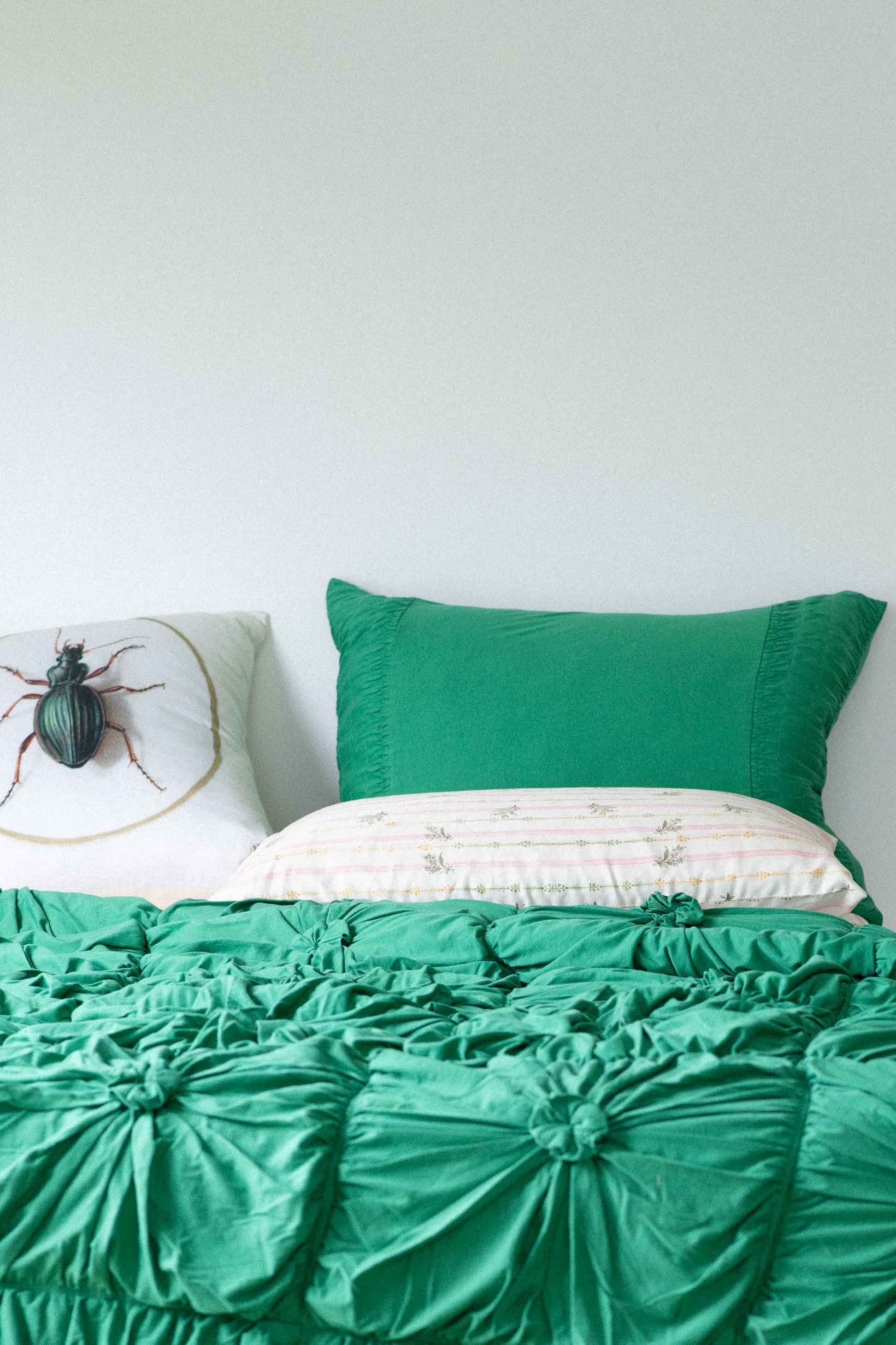 Green rosette moth cushion on bed