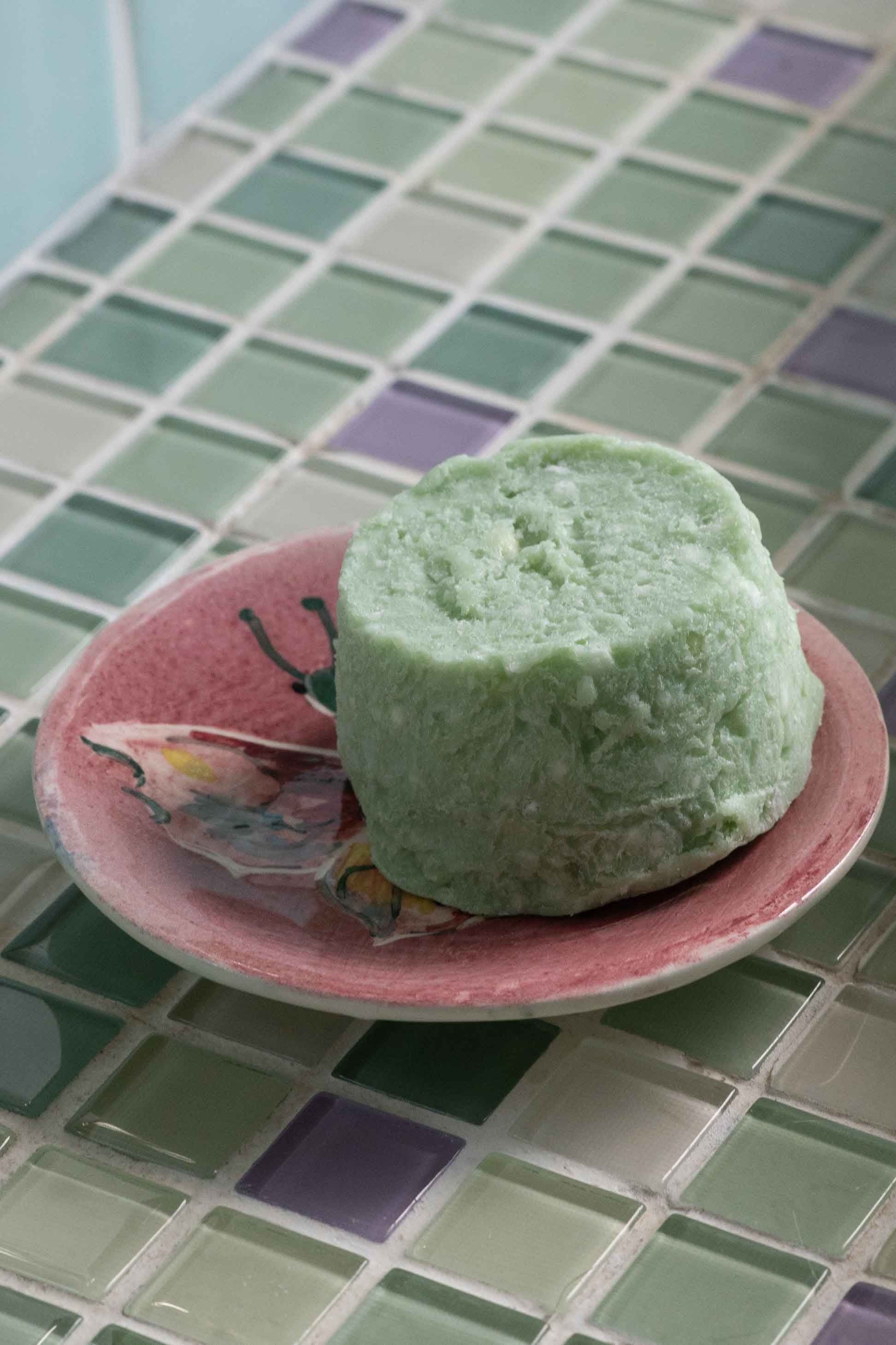 Green shampoo bar on pink dish
