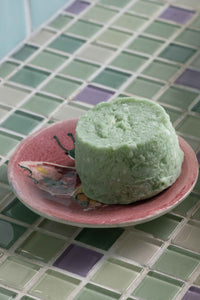 Green shampoo bar on pink dish