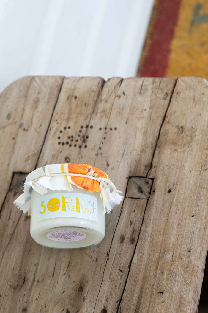 Sorry Candle on rustic wooden surface