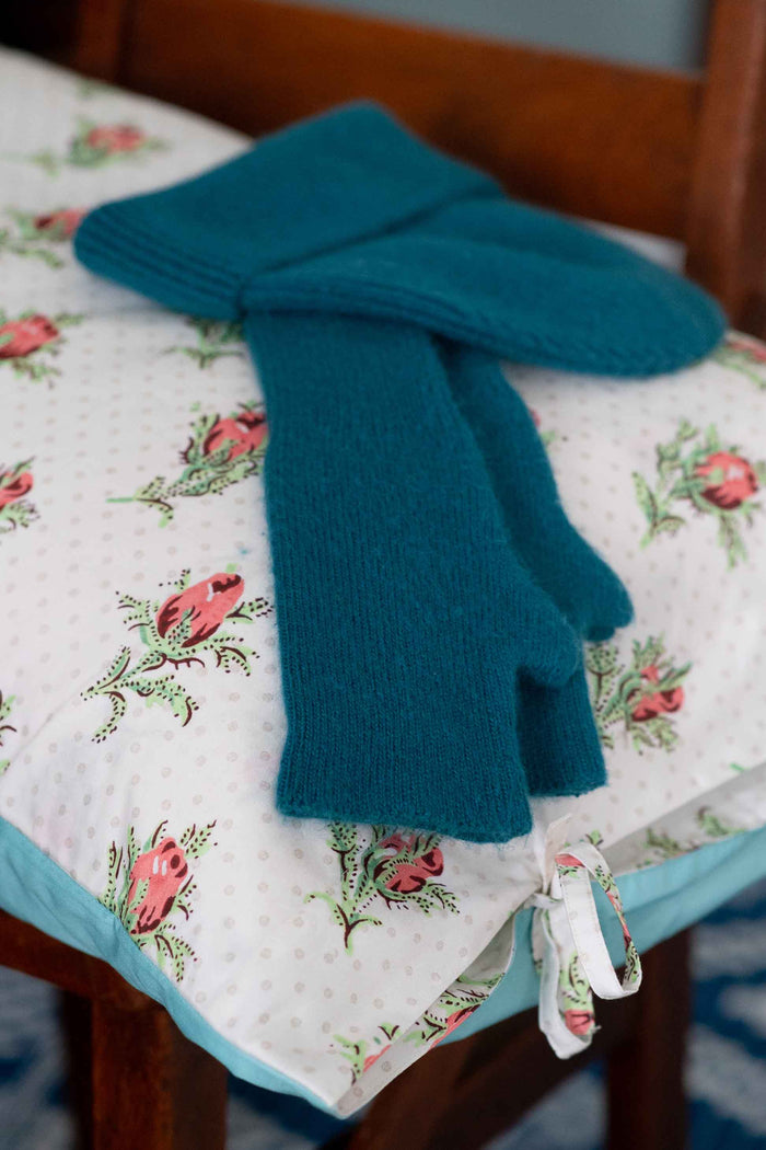 Teal gloves and beanie on peony pillowcase