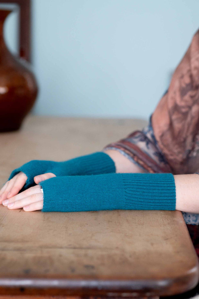 Teal fingerless gloves on wooden table