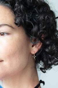 Tiny cross earrings on woman