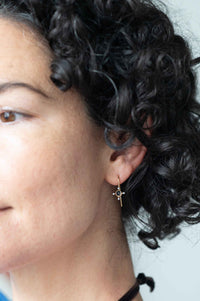 Tiny cross earrings on woman