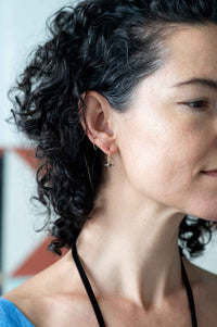 Tiny gold earrings on woman's ear