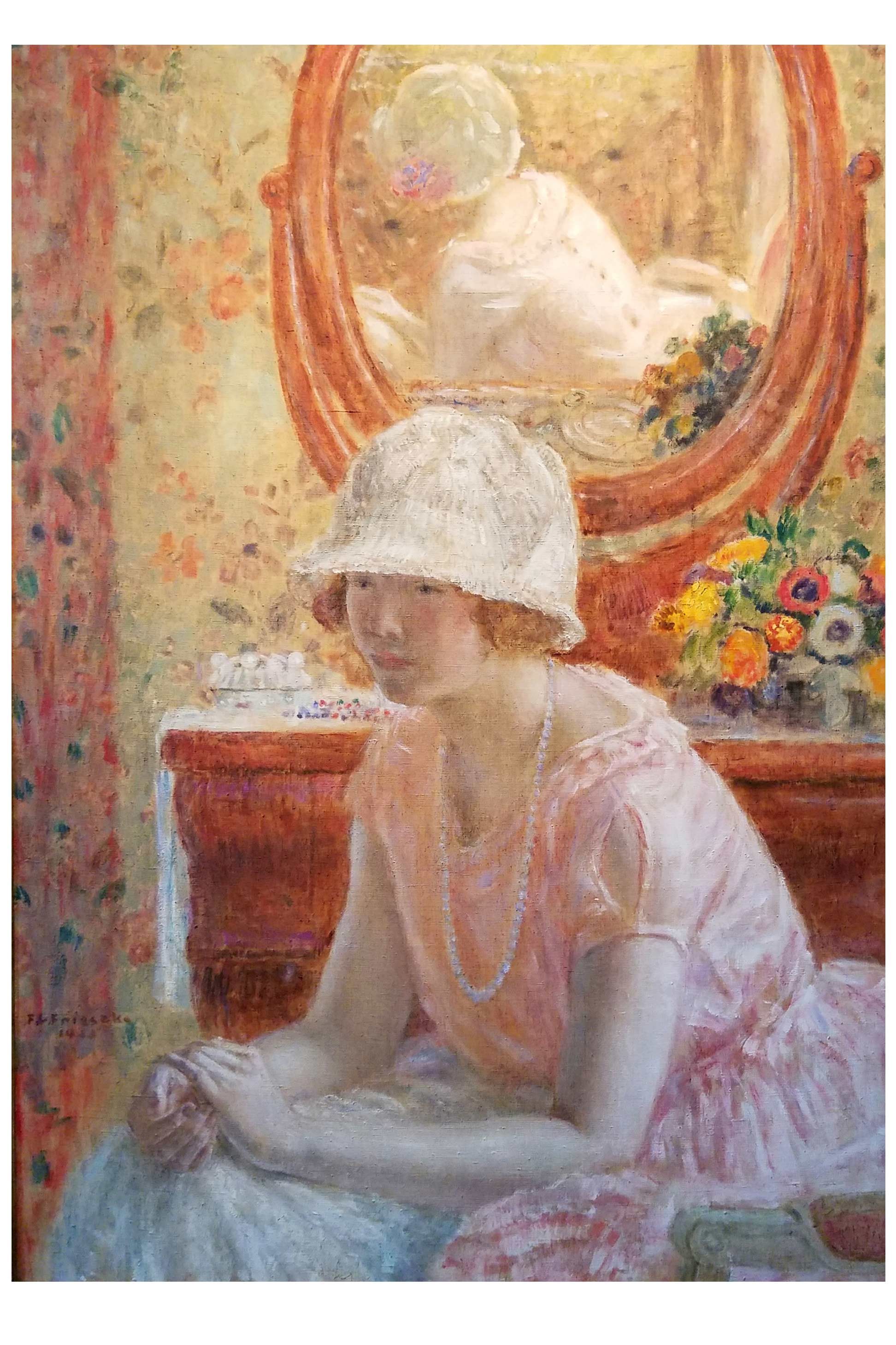 Woman in a pink dress and hat sitting in front of a mirror.