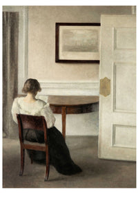 Woman seated in a room, facing away, with a table and open door.