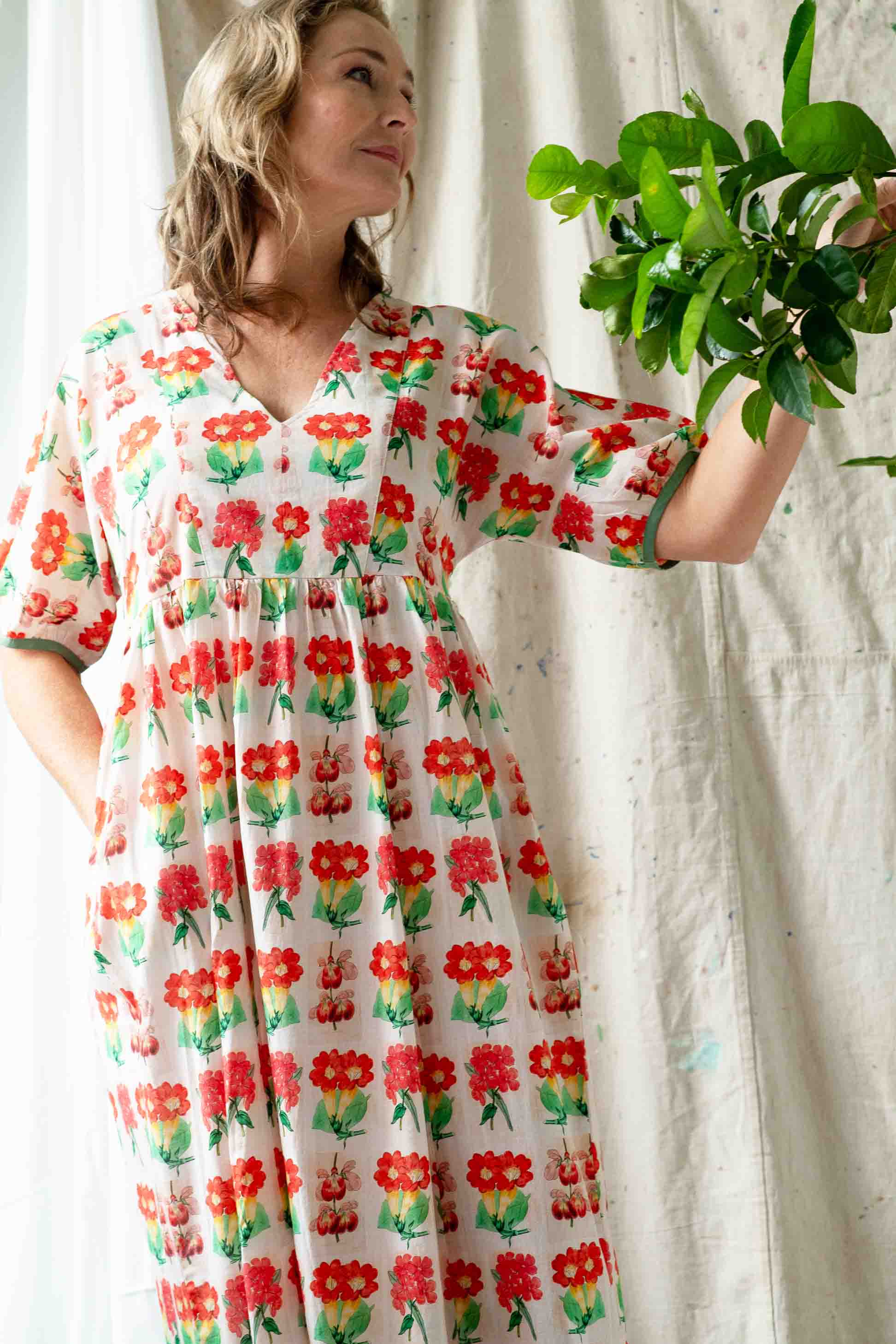 Celia Florabelle in floral dress holding plant