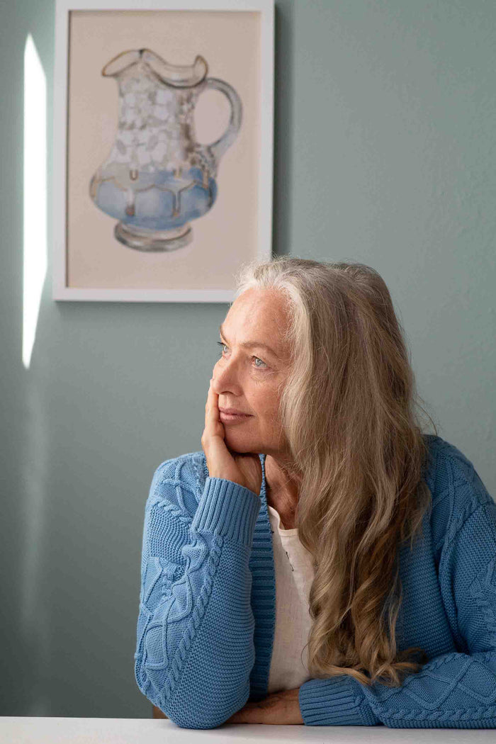 Woman Charli Lichen Valeria Cream, blue cardigan, looking at pitcher art