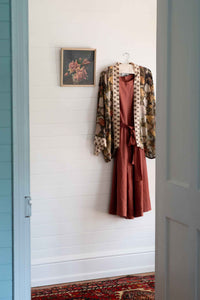 Dress and jacket hanging on a white wall.