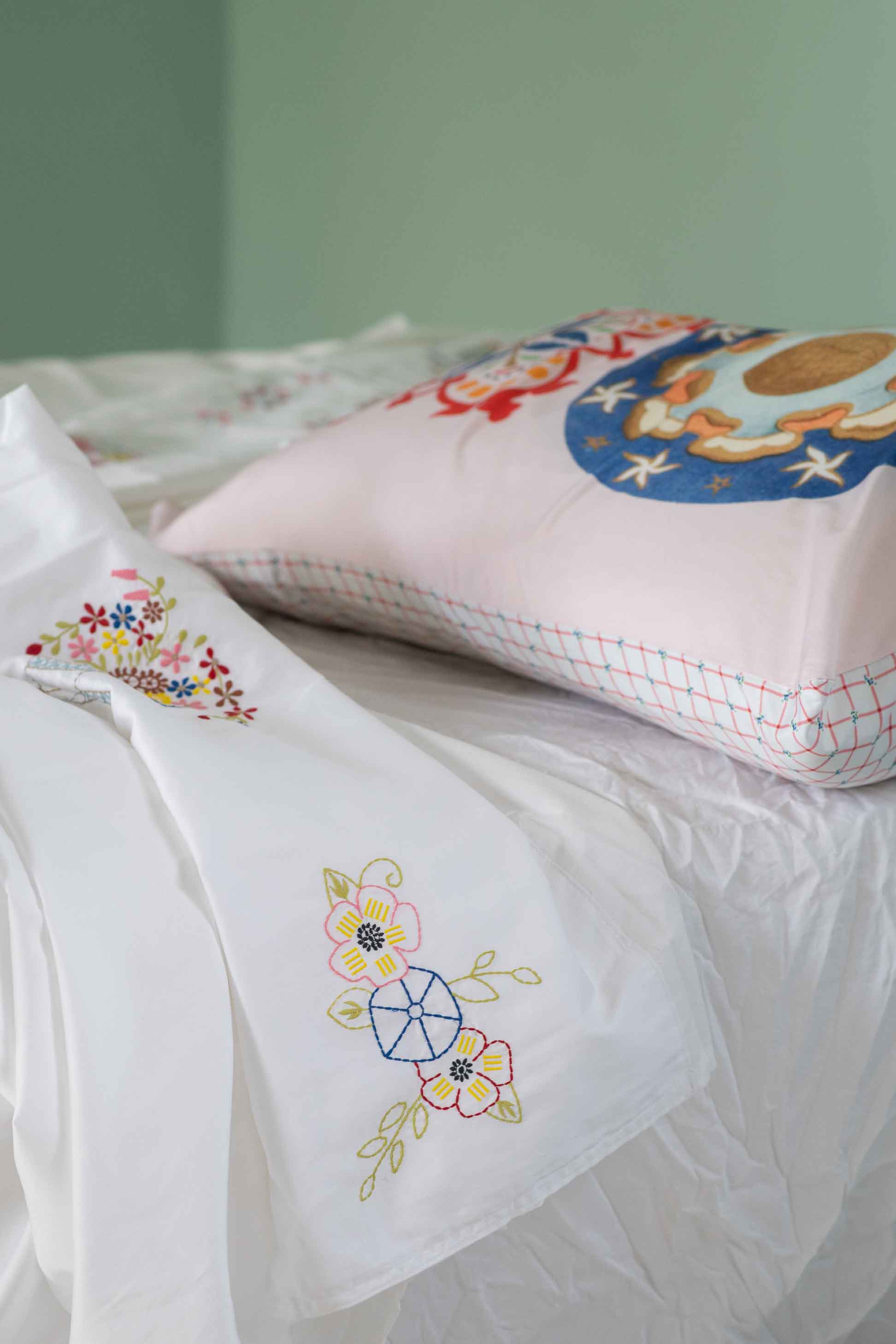 Embroidered pillow and linens on bed - DSC4617
