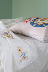Embroidered pillow and linens on bed - DSC4617