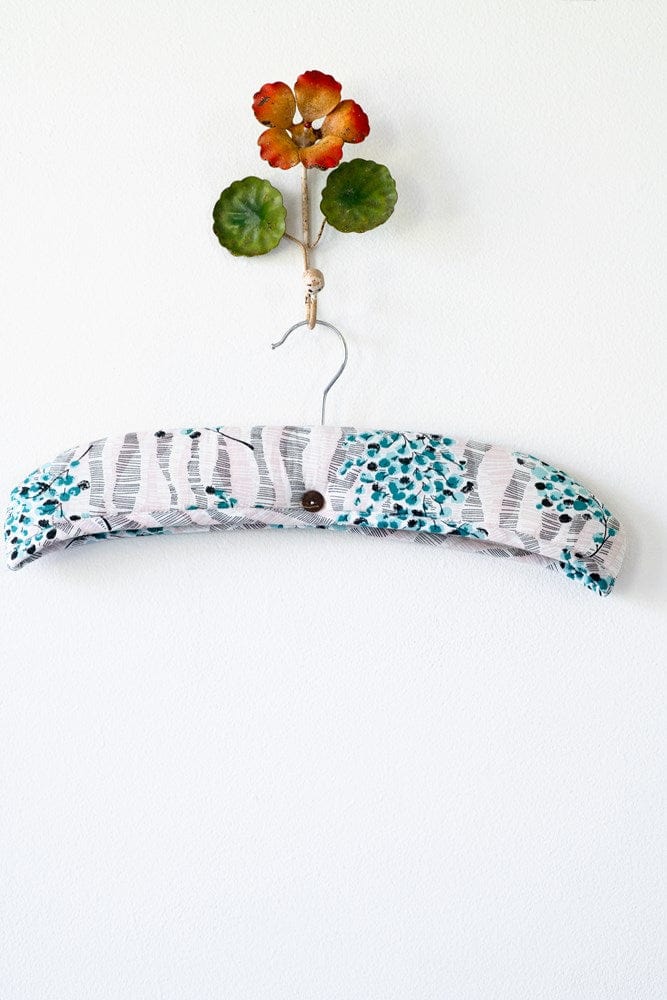 Decorative fabric-covered hanger with flower accent.