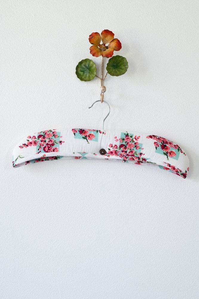 Floral padded hanger with decorative flower.