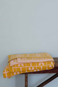 Yellow daisy throw blanket folded on wooden surface