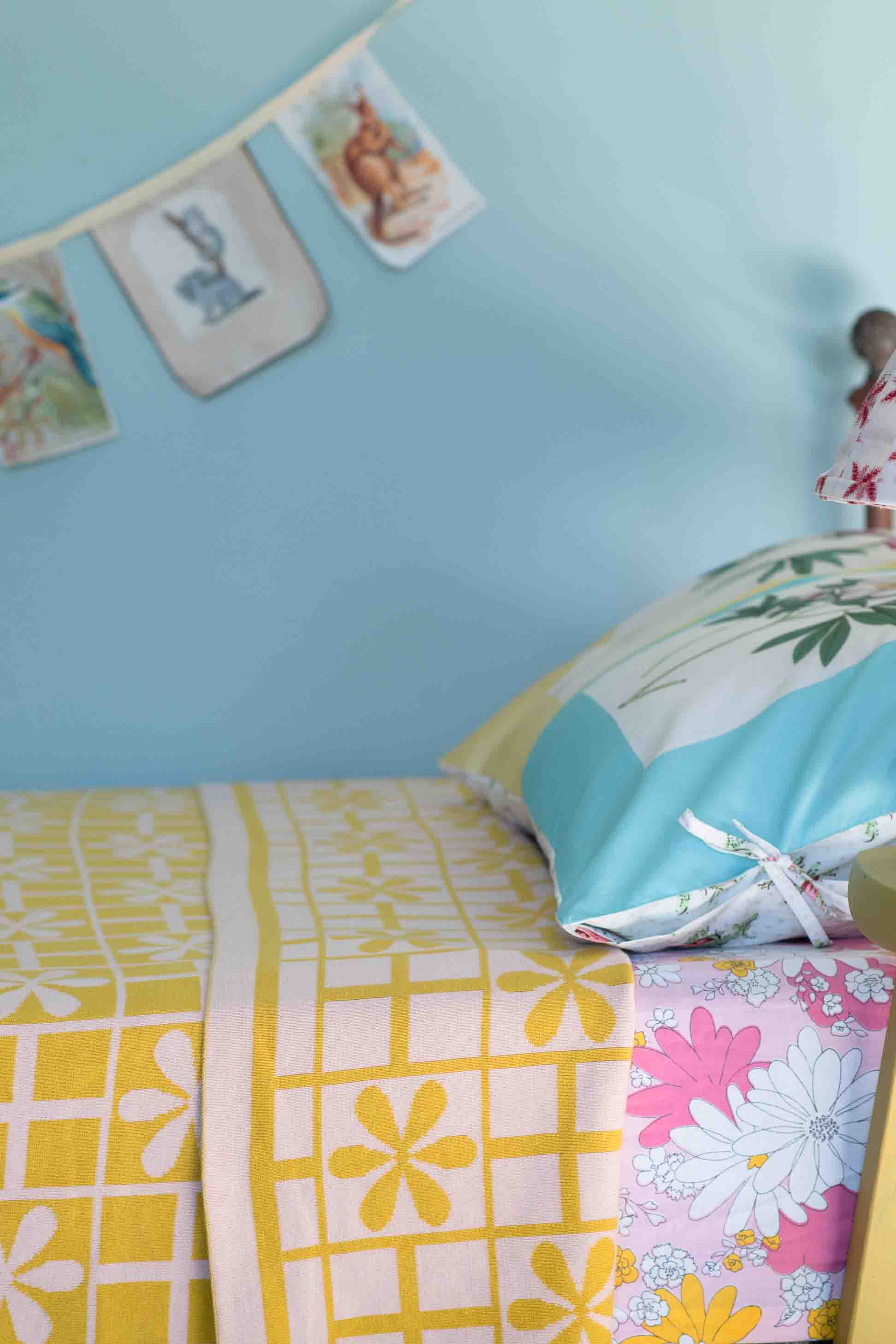 Daisy throw on bed with floral pillow and banner