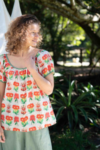 EttaFlorabelle in floral top smiling outdoors.