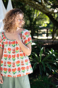 EttaFlorabelle in floral top smiling outdoors.