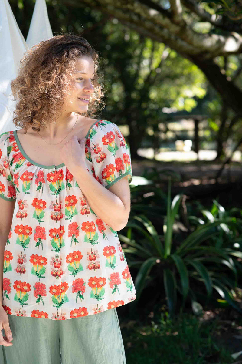 EttaFlorabelle in floral top smiling outdoors.