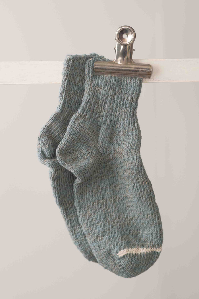 Light blue knitted socks hanging on clip