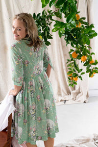 Gianna Newlyn in floral dress, citrus tree in background.