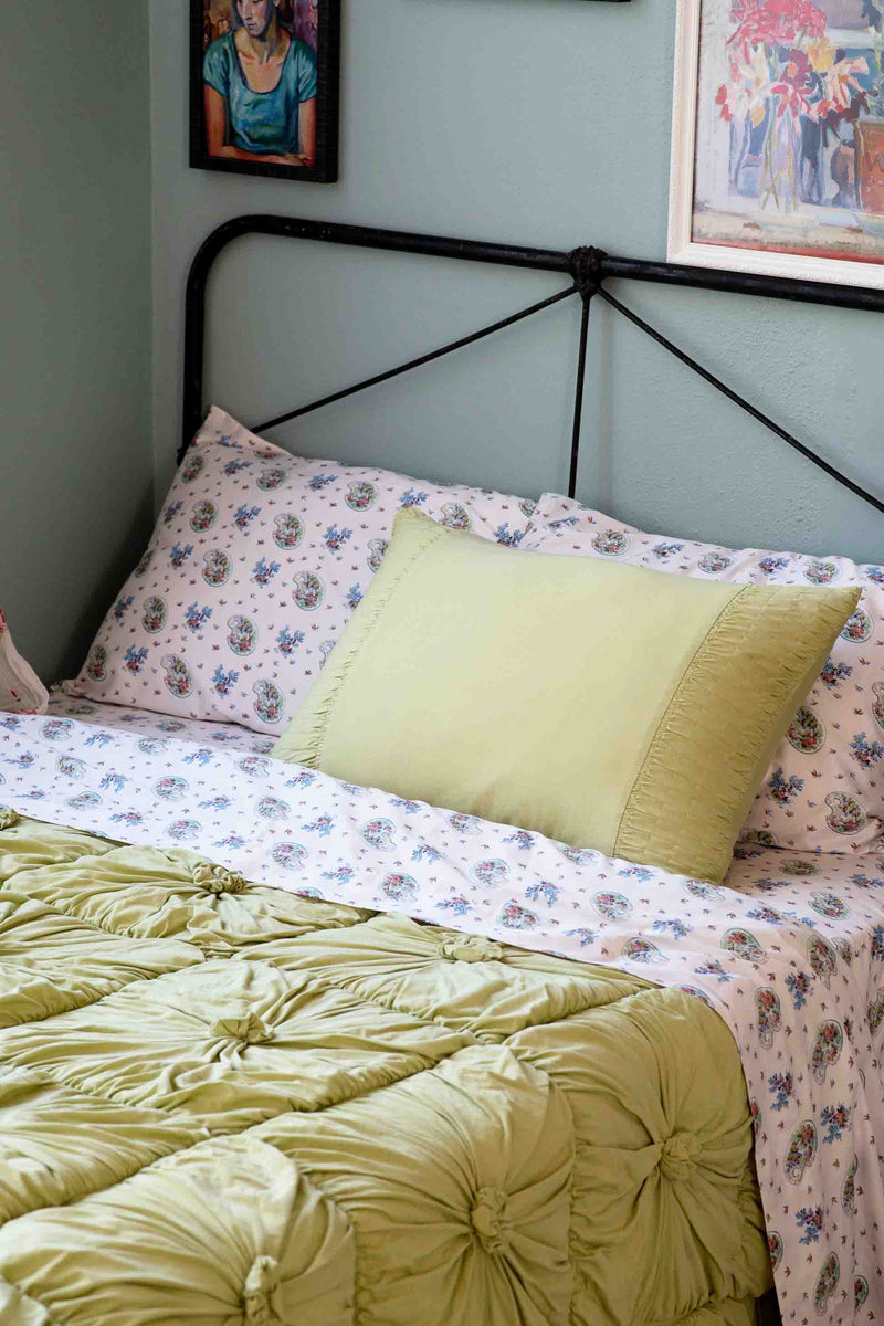 Green tea rosette bed with green pillow and floral sheets.